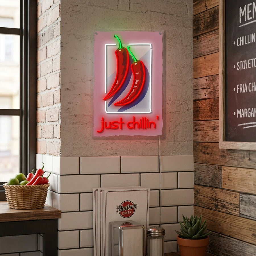 A cozy living room setting featuring a lit 'Just Chillin' neon sign mounted on the wall above comfortable seating, creating a relaxed atmosphere.