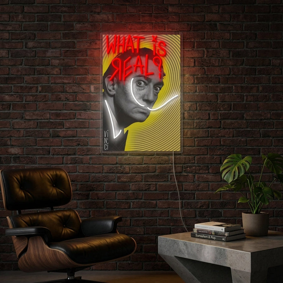 Philosophical 'What Is Real?' neon sign illuminated on a exposed brick wall in a cozy living room, next to a comfy armchair and bookshelf.