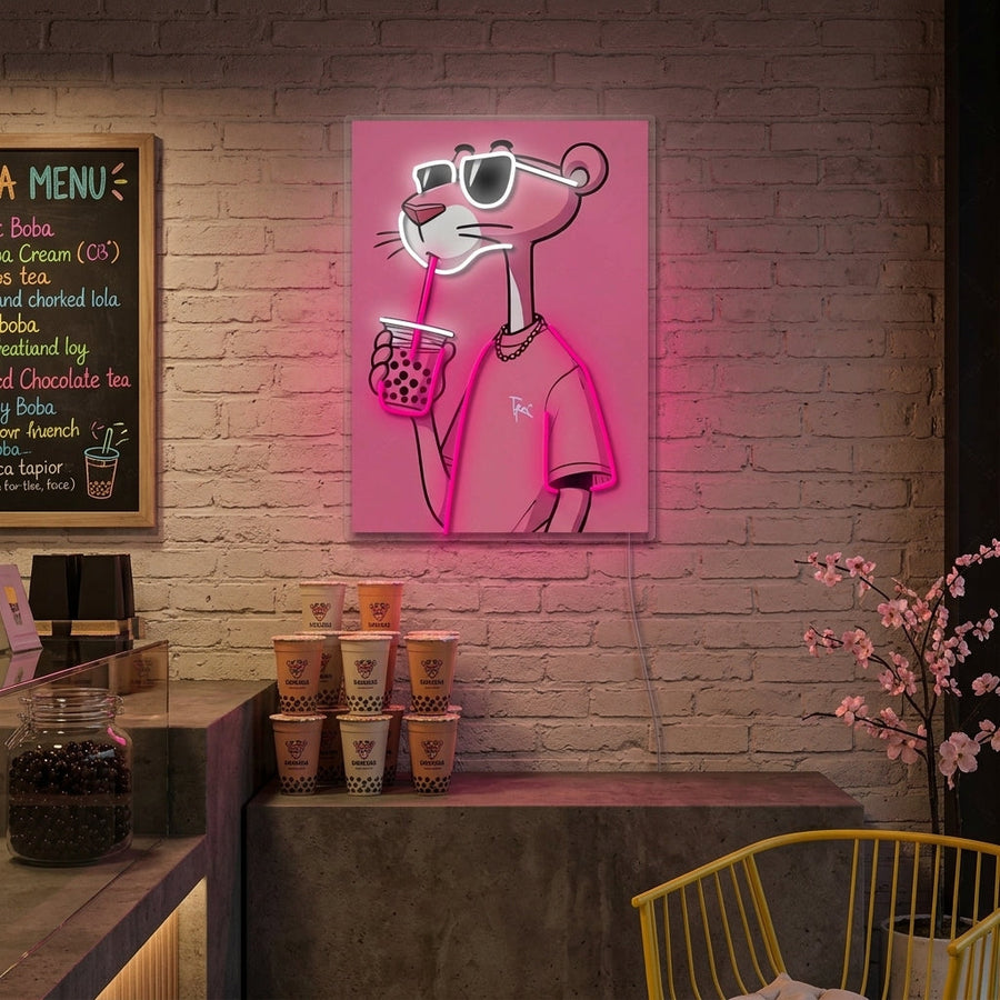 A wall-mounted glowing neon sign featuring the character Pink Panther holding a boba tea with a straw, placed in a modern living room or cafe setting above a chair and table.