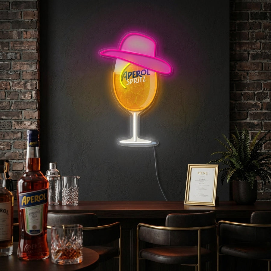 Miss Aperol vibrant orange neon sign displayed on a brick wall above a bar setup with cocktails and ingredients.