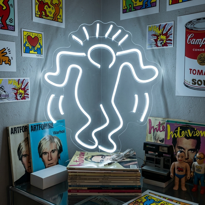 A close-up shot of the white neon sign showing a stylized outline of a person dancing on an acrylic backer against a rustic brick wall.