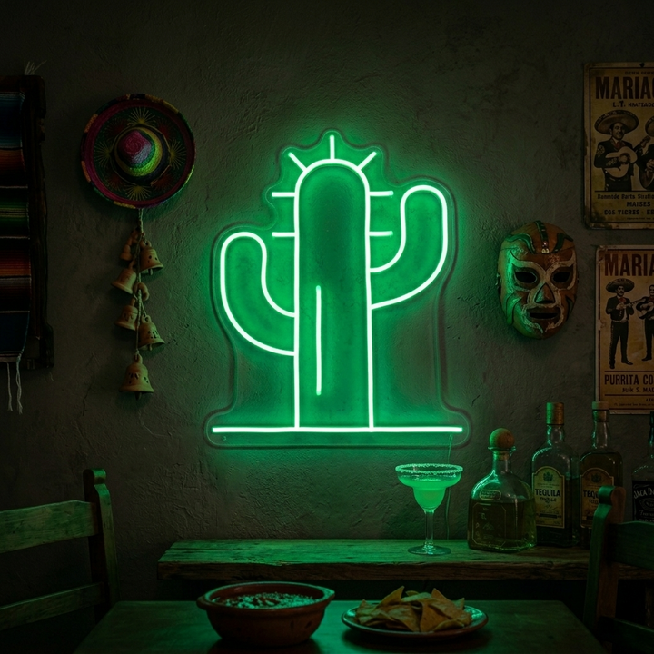 A bright green cactus neon sign with pink flower glowing on a shelf with various decor items.