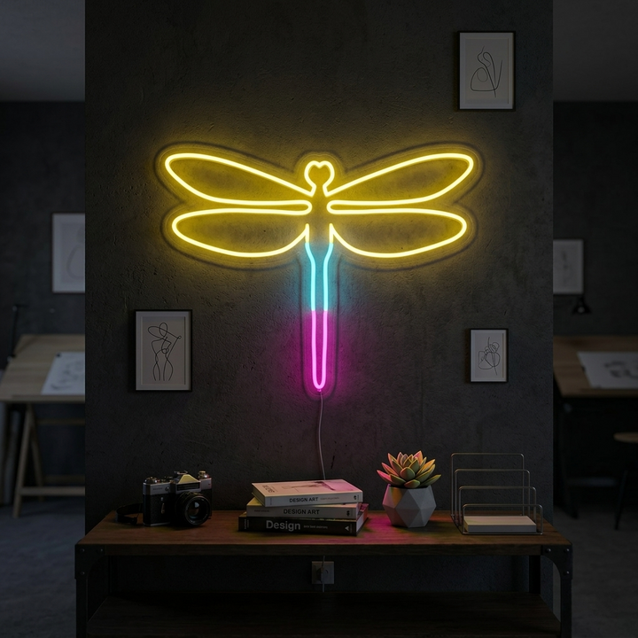 An illuminated Dragonfly neon sign displayed on a subtle bedroom wall above a plant, glowing softly.