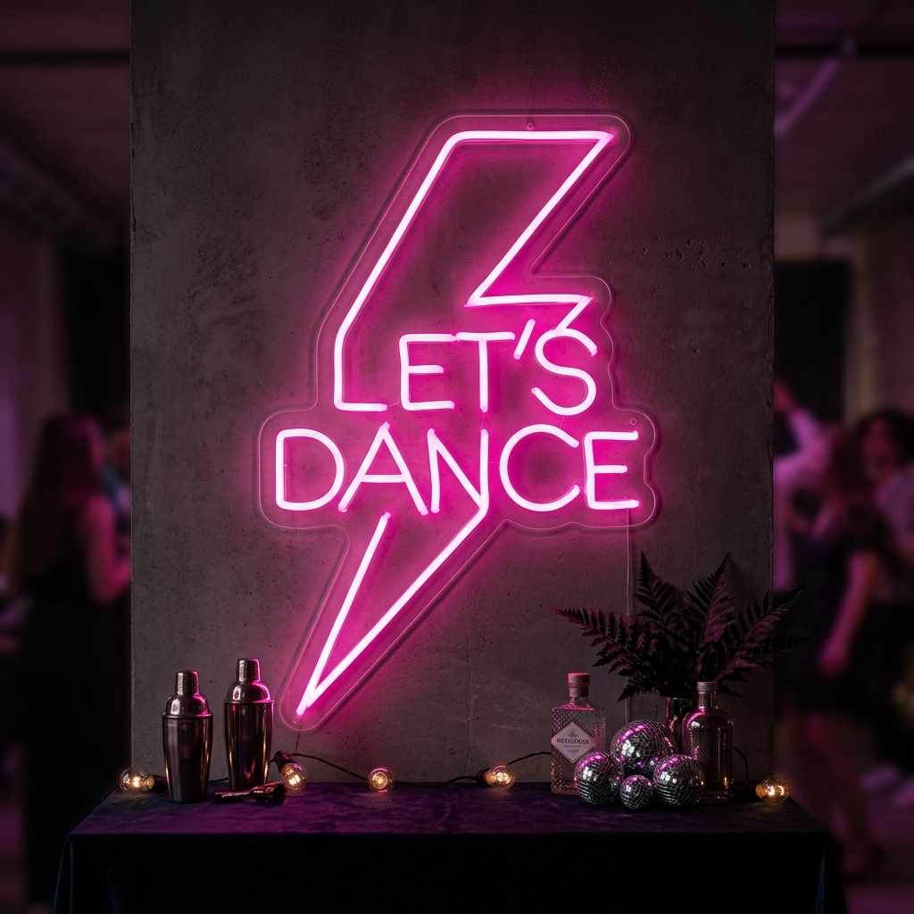 Vibrant pink 'Lets Dance' neon wall sign glowing above a lively party crowd, creating a high-energy dance floor atmosphere.