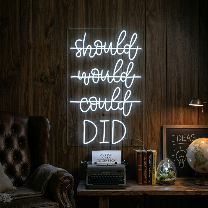 A vibrant 'Should Would Could Did' neon sign mounted on a textured wall, glowing brightly.