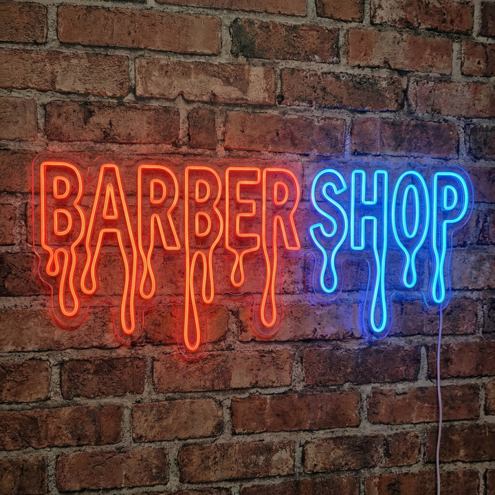A close-up photograph of a lighted 'Barbershop' neon sign mounted on a brick wall, showcasing the physical tubing.