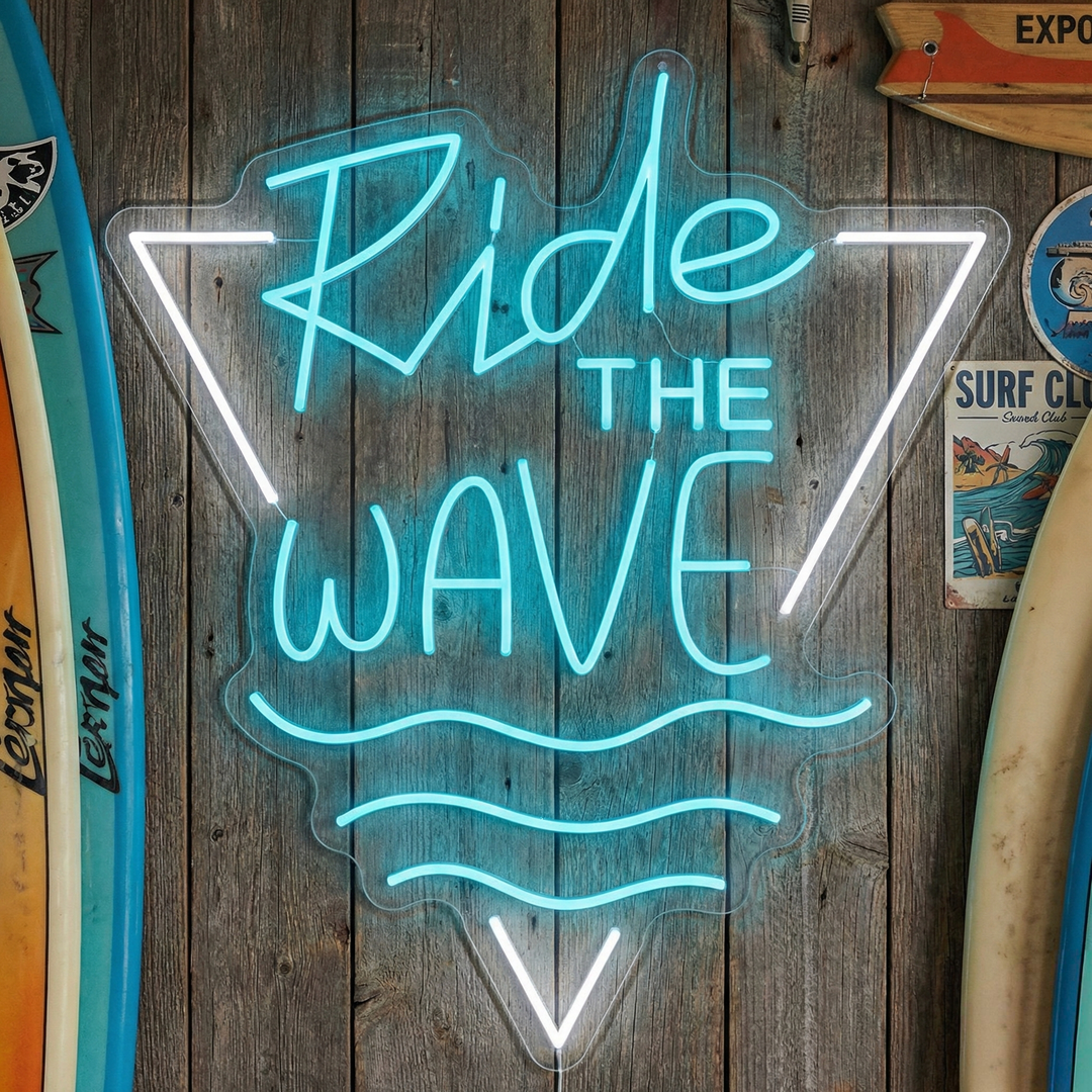 A glowing 'Ride The Wave' neon sign mounted on a weathered wood wall, surrounded by surfboards and other coastal decor in a beach house setting.