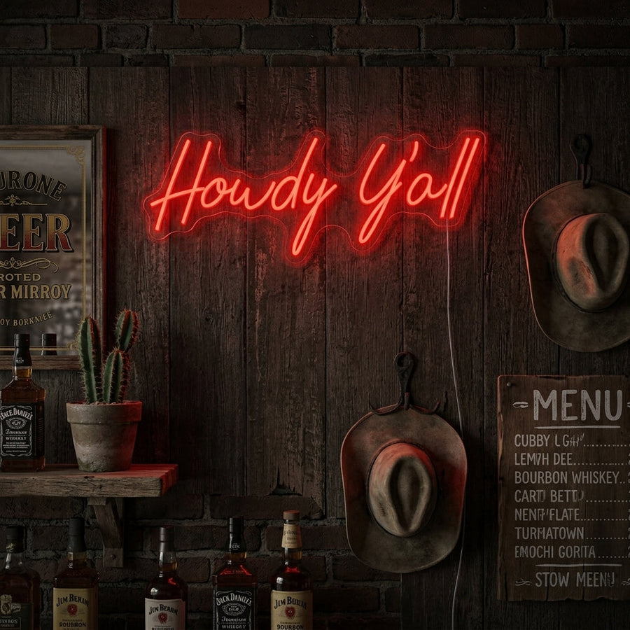 A lifestyle mockup showing the glowing yellow 'Howdy Y'all' neon sign styled on a textured wooden wall above a console table with western-themed decor.