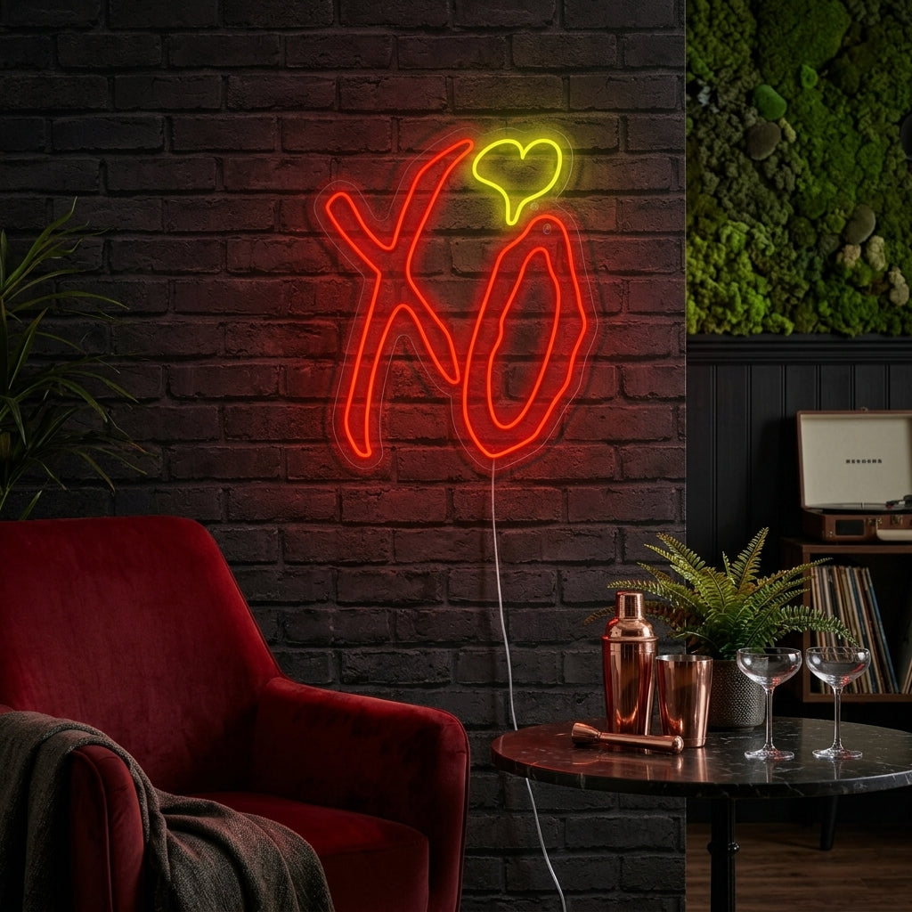 A candid, atmospheric photograph showing the pink glowing "XO" neon sign mounted on a textured brick wall within a cozy, contemporary living room setting with soft background bokeh.