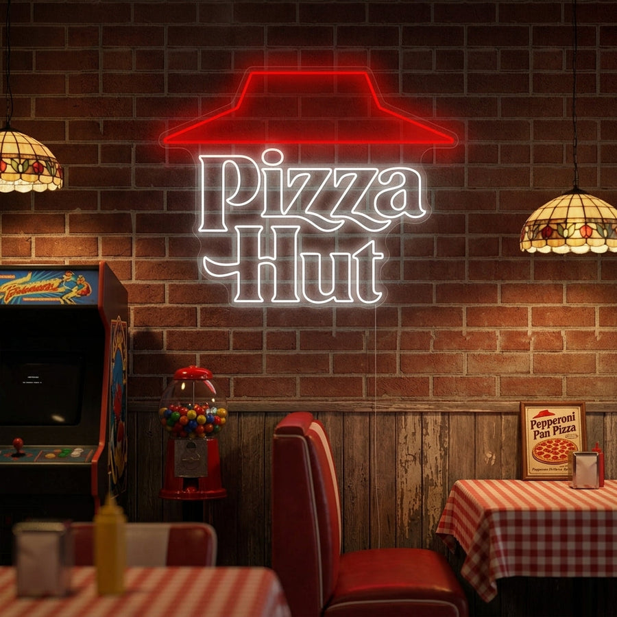Pizza Hut neon sign showing the red logo and text on a textured brick wall with red booth seating in a restaurant setting