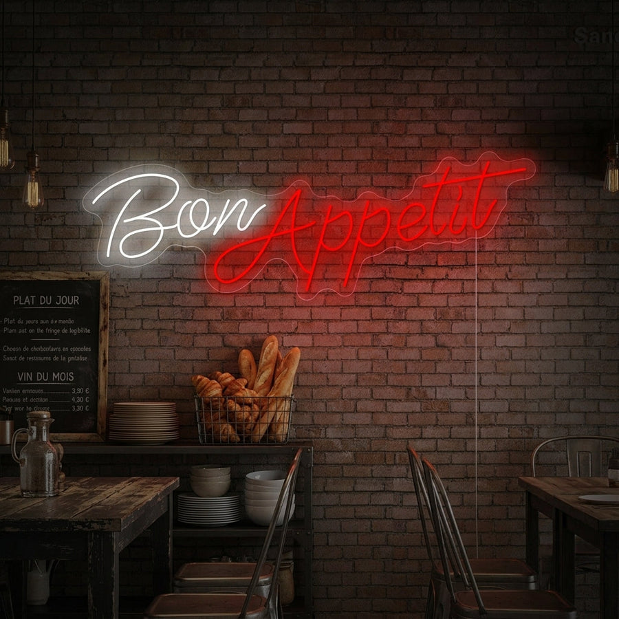 A stylish 'Bon Appetit' cursive neon sign glowing warmly above a sleek, modern kitchen counter set with wine glasses and bread, adding a welcoming ambiance.