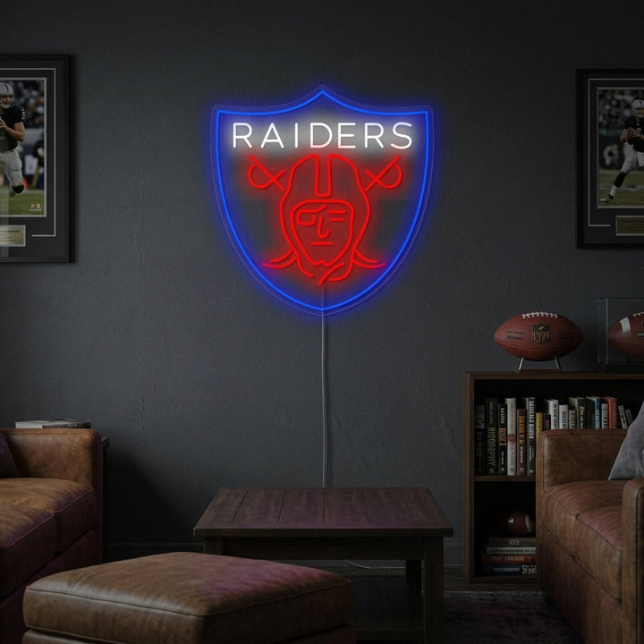 Handmade Raiders shield logo neon sign glowing vibrantly in a home game room setting