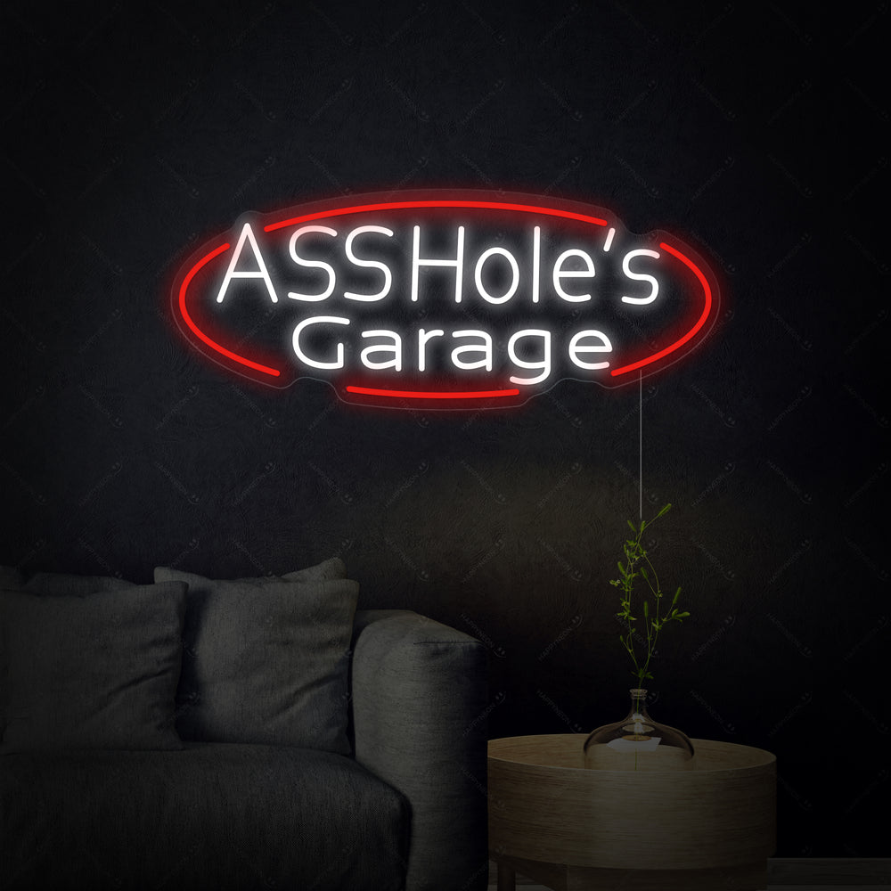 A close-up view of the 'Assholes Garage' neon sign glowing brightly on a wall.