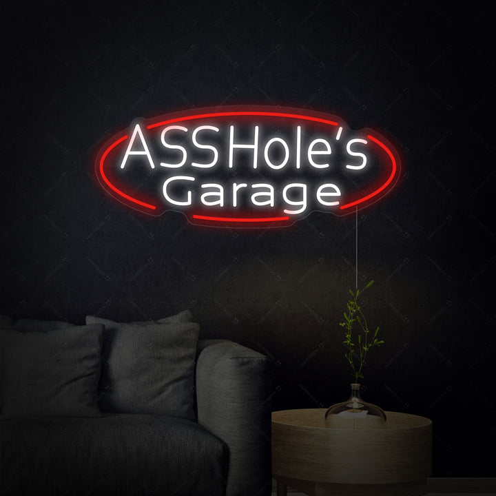 A close-up view of the 'Assholes Garage' neon sign glowing brightly on a wall.