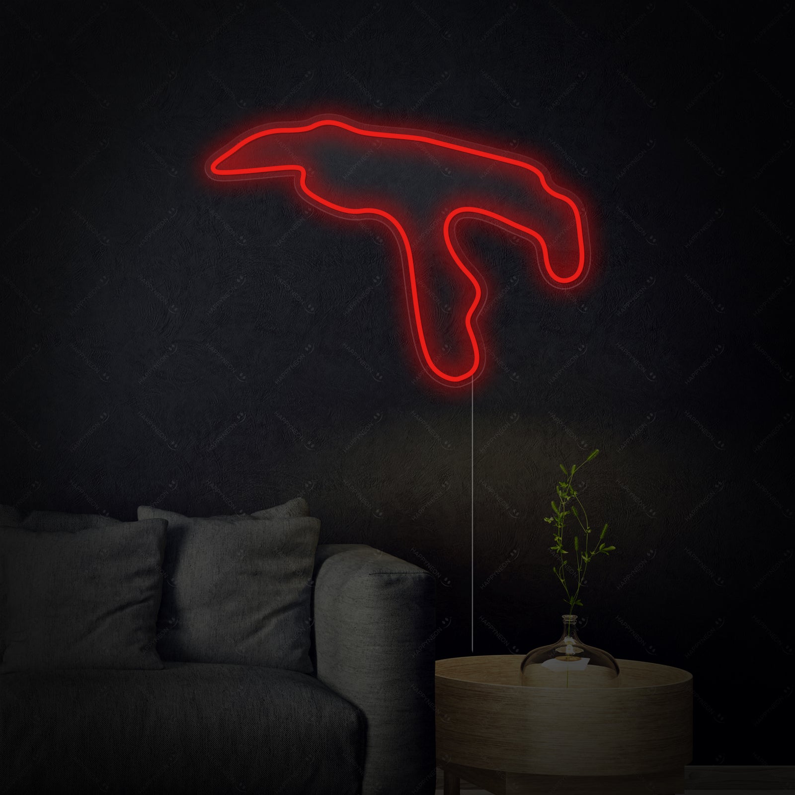 A glowing blue neon sign depicting the Belgium F1 circuit layout mounted centrally on a textured gray wall above a dark shelf, casting a blue light.