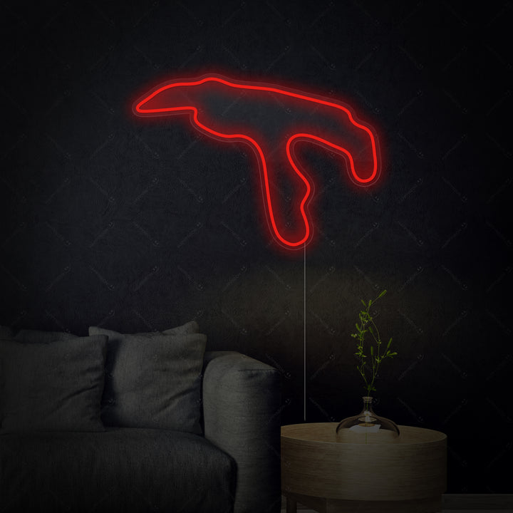 A glowing blue neon sign depicting the Belgium F1 circuit layout mounted centrally on a textured gray wall above a dark shelf, casting a blue light.