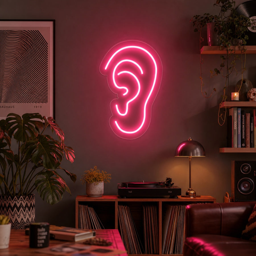 A creative neon wall sign shaped like an ear, glowing with electric light in a contemporary room setting.
