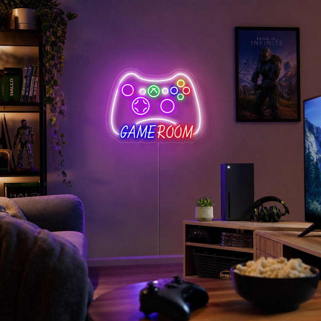 A glowing blue and pink neon sign shaped like a game controller hanging on a brick wall, illuminating a cozy gaming corner with a monitor and keyboard.