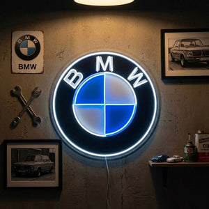 A vibrant German performance car neon sign glowing red, white, and blue mounted in a clean, modern garage environment.
