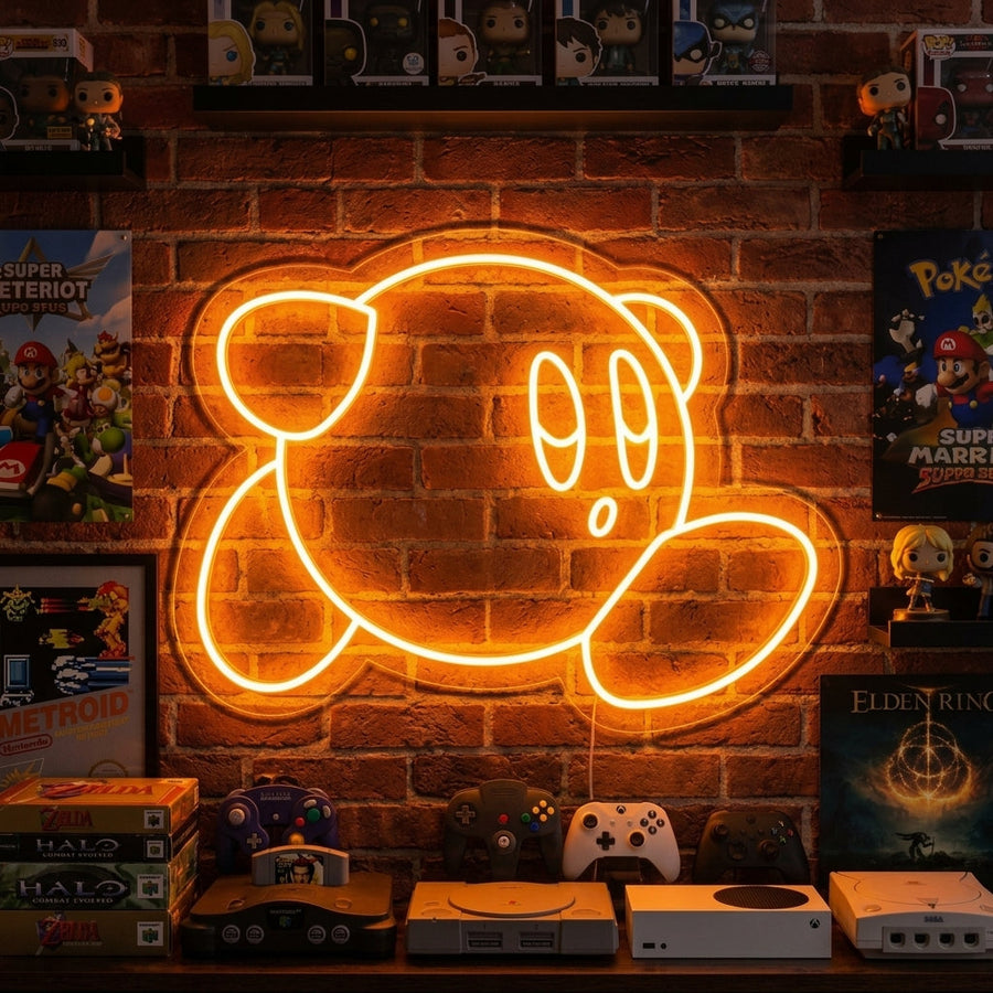 A cute round pink game character neon sign glows with vibrant pink and blue light on a clean brick wall in a cozy room setting.