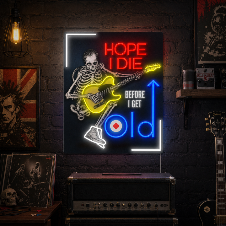 A rectangular 'Hope I Die Before I Get Old' neon sign with blue text and a detailed yellow and blue punk skull graphic with headphones, mounted on a dark brick wall.
