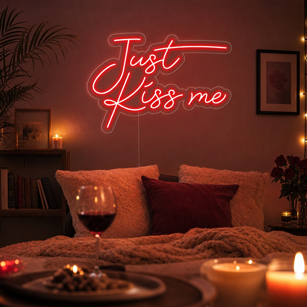A glowing 'Just Kiss Me' neon sign on a wall in a chic room setting.