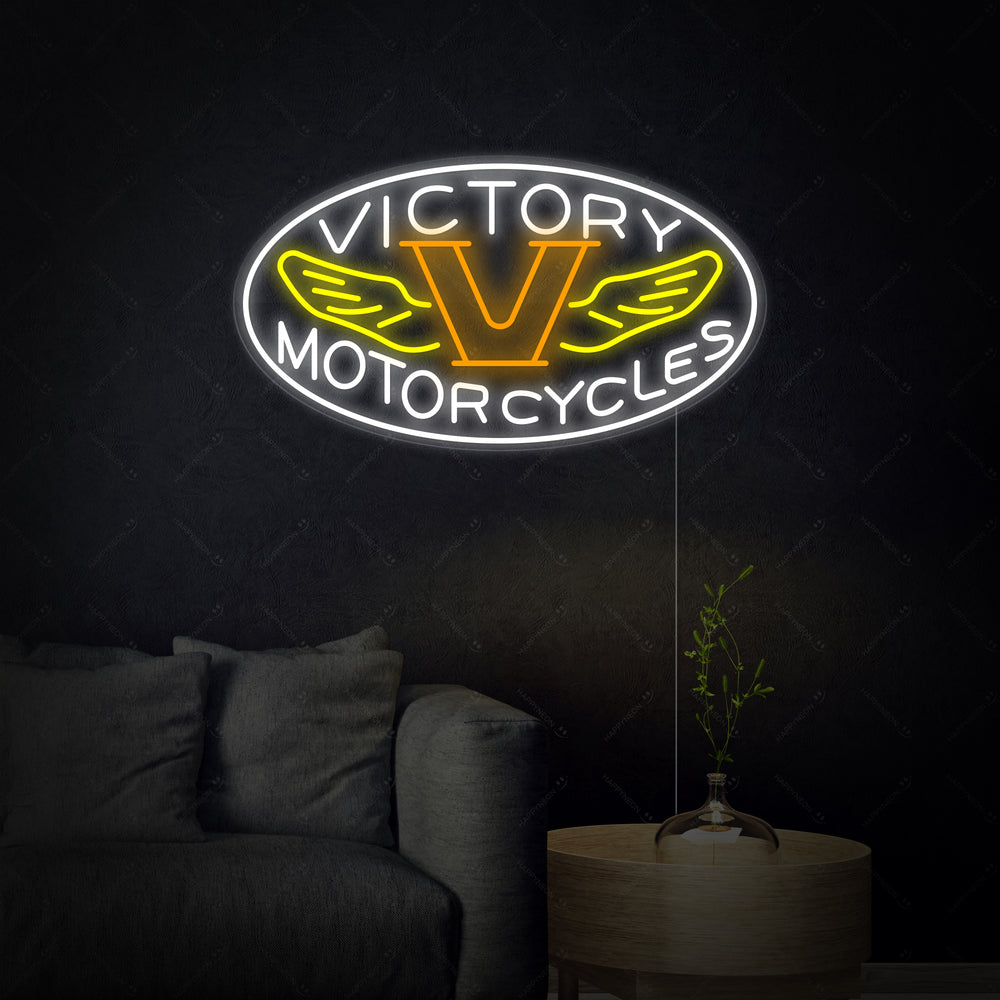 A close-up view of the 'Motorcycles Victory' neon sign, showing the detailed blue and red neon tubes mounted on a clear backer, with subtle wiring details visible.