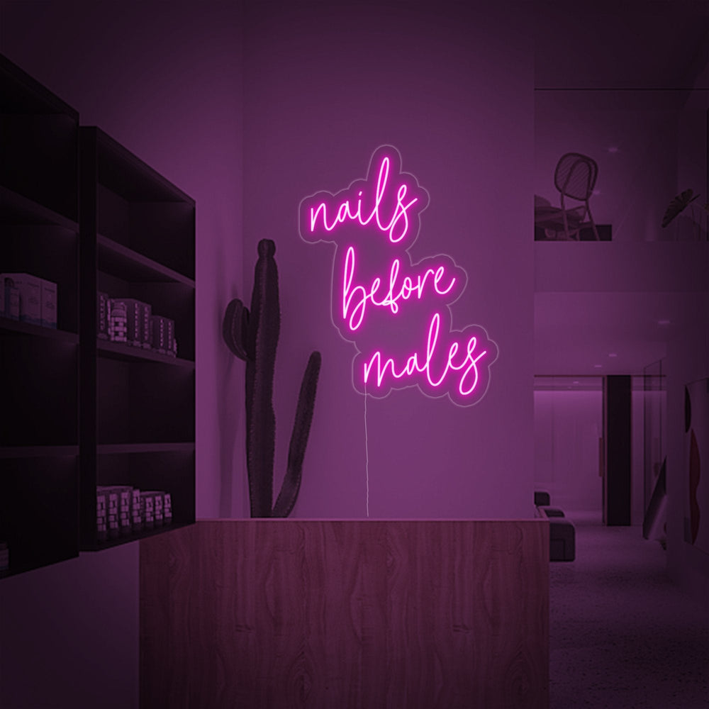 The 'Nails Before Males' neon sign glowing brightly in an urban interior setting, adding a vibrant, pink accent to the decor.