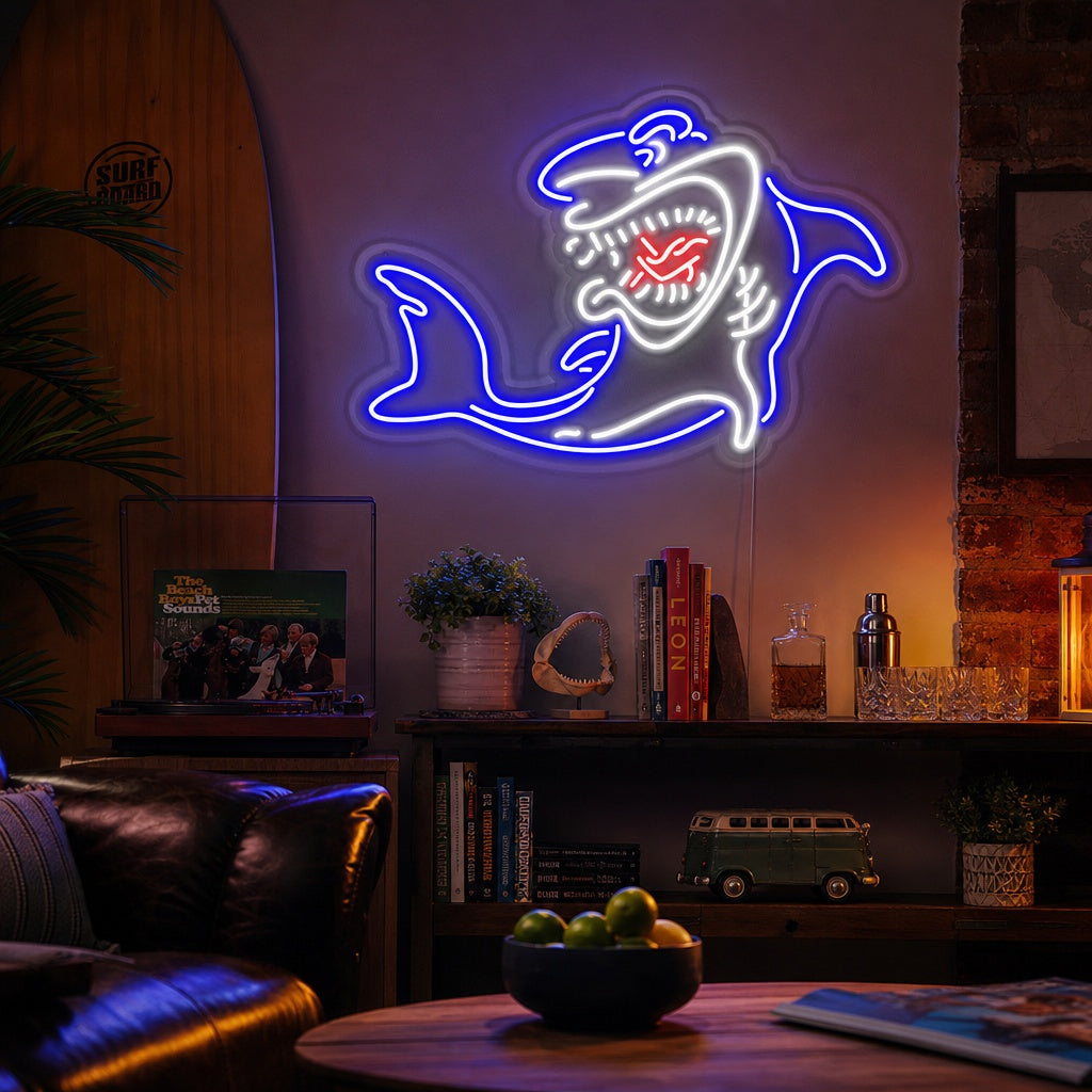 A vibrant 'Shark' neon wall sign, depicting a glowing blue silhouette of a shark, mounted and lit up in a modern living room setting.