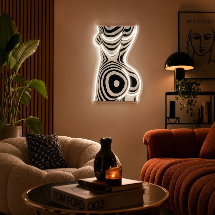 UV print neon sign depicting an abstract woman's body silhouette with a zebra pattern fill, glowing brightly on a wall.