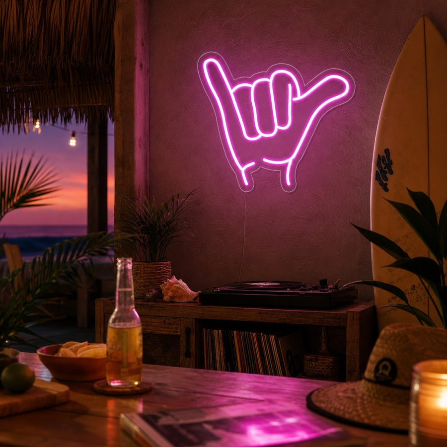 The "Shaka" hand gesture neon sign glowing on a textured wall in a modern living room setting.