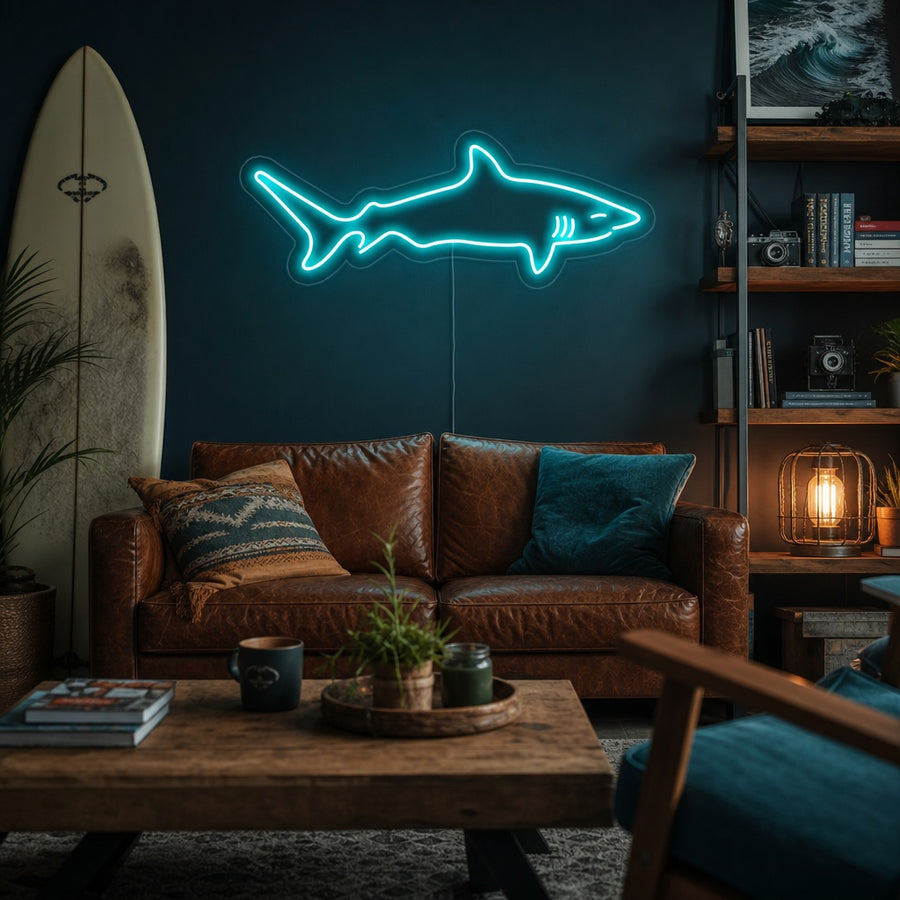 A bright blue shark neon sign mounted on a bedroom wall above a shelf with ocean decor, casting a cool glow across the room.