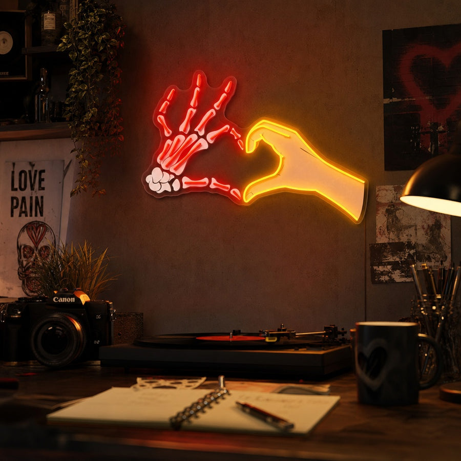 Skull hand making love sign pose glow neon sign on wall in bedroom setting with bed, plants, and other decorations
