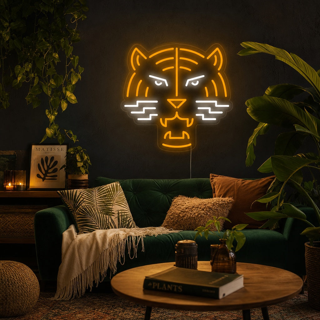A vibrant 'Tiger Head' neon wall sign in white and yellow glowing brightly above a cozy bed with decorative pillows and plants in a room.