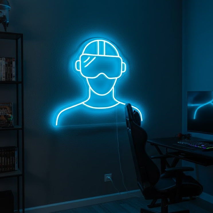 A vibrant VR headset neon sign featuring a glowing silhouette with blue accents and a clear acrylic backing, displayed on a stylized brick wall in a modern gaming room setup.