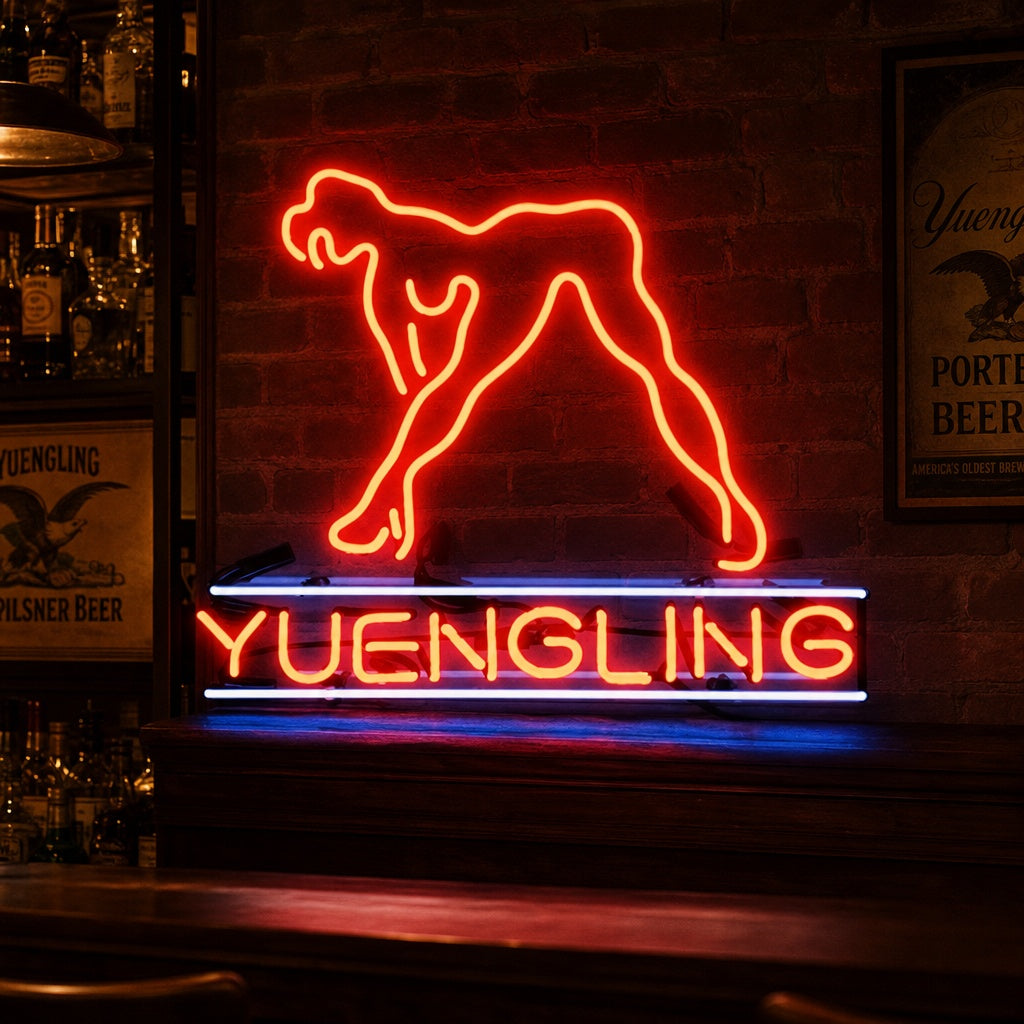 A close-up photograph of a fabricated 'Yuengling Live Nudes Girl' neon sign, featuring detailed tube shaping, visible wiring, and a central transformer, unlit.