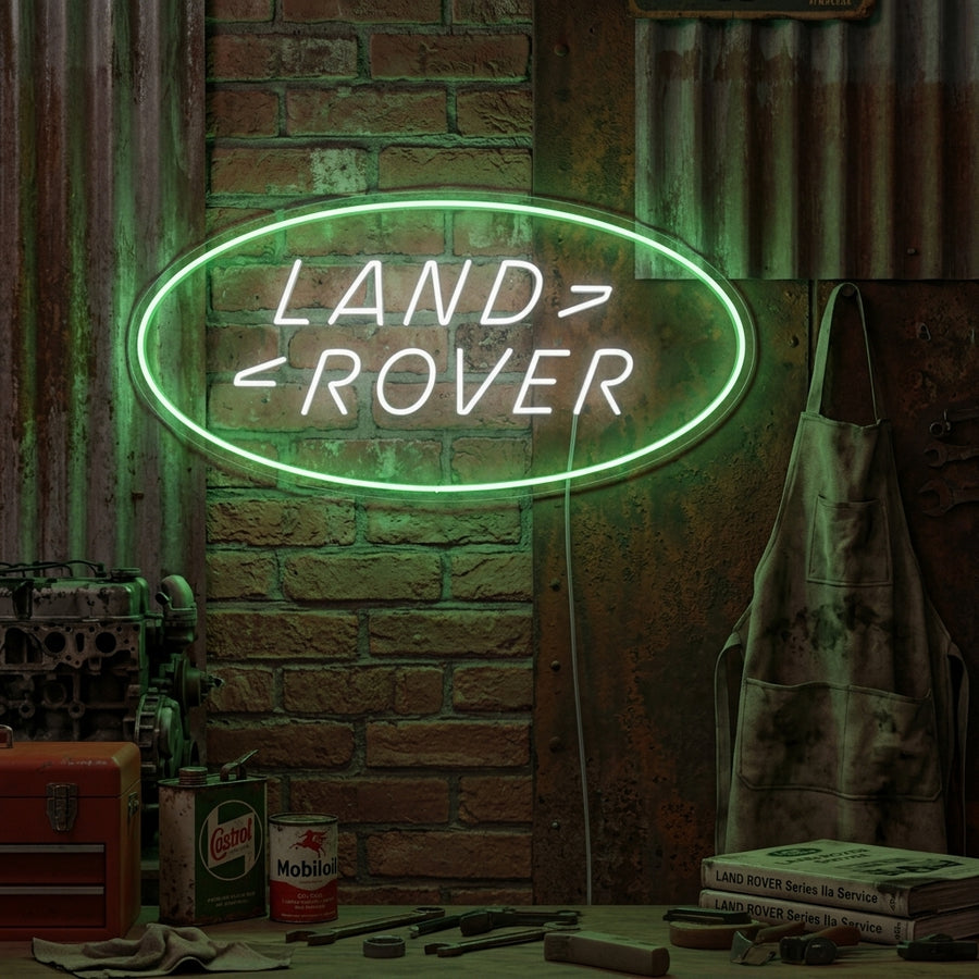 Land Rover logo neon sign glow in a workshop garage environment.