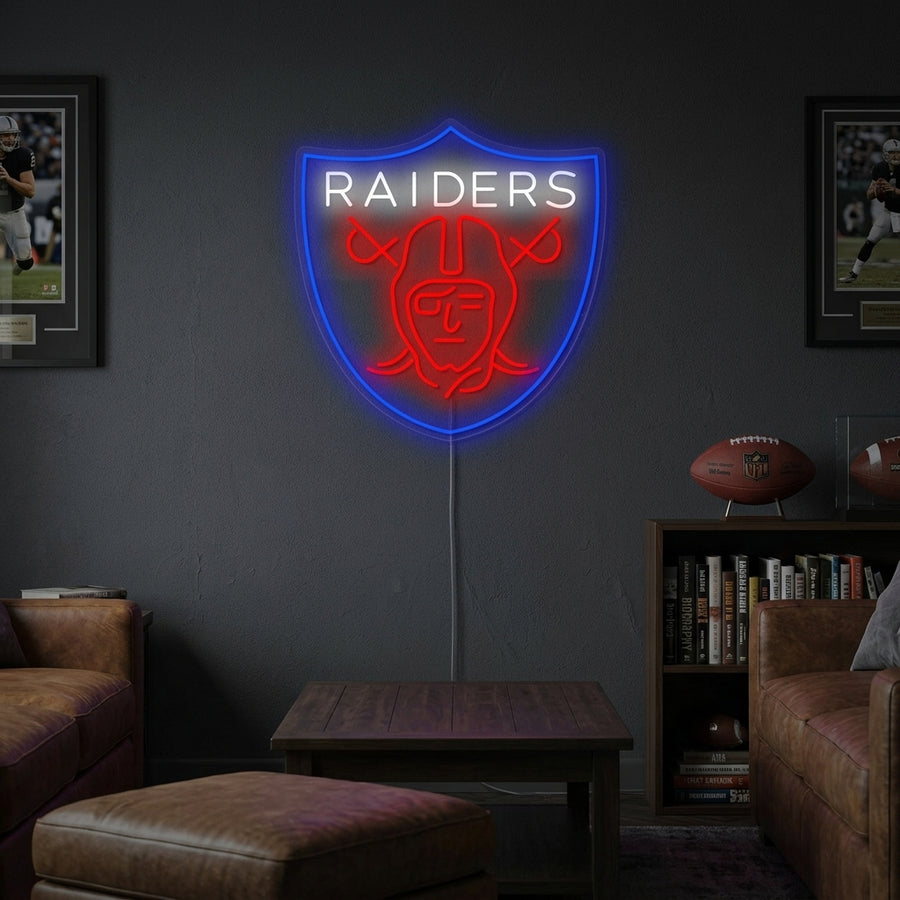 Handmade Raiders shield logo neon sign glowing vibrantly in a home game room setting