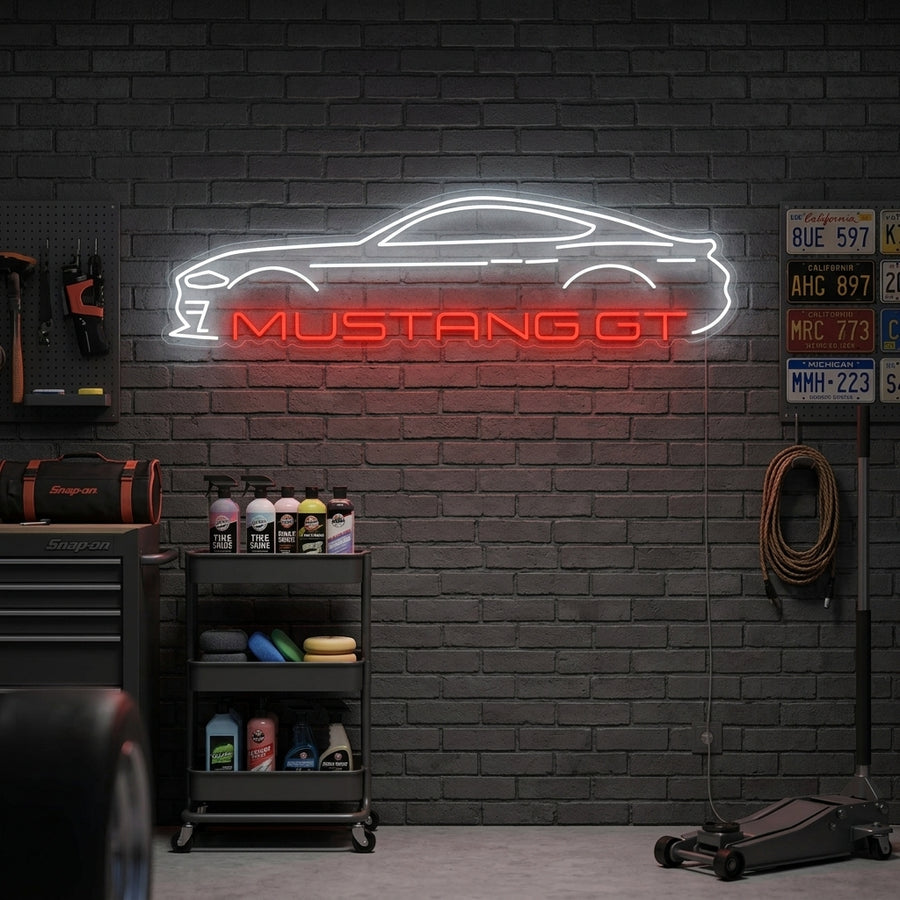 Mustang GT neon sign mounted on a brick wall in a garage setting with a classic blue Mustang below