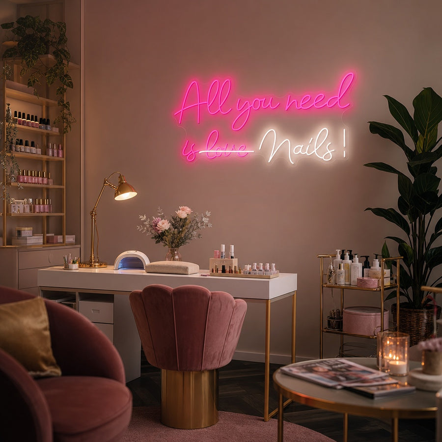 Vibrant pink neon sign reading "All You Need Is Nails" mounted on a brick wall above a chic velvet salon chair.