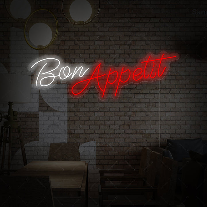 Close-up photograph of the 'Bon Appetit' script neon sign with clear backing, showing the glowing white text.