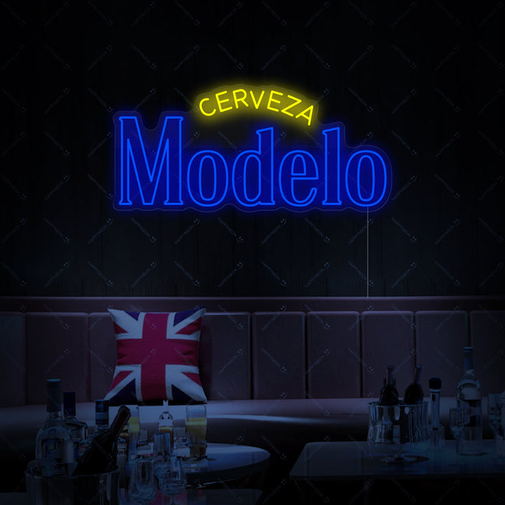 Close-up detailed view of the Cerveza Modelo neon sign, displaying the classic script and blue and gold branding on a dark background