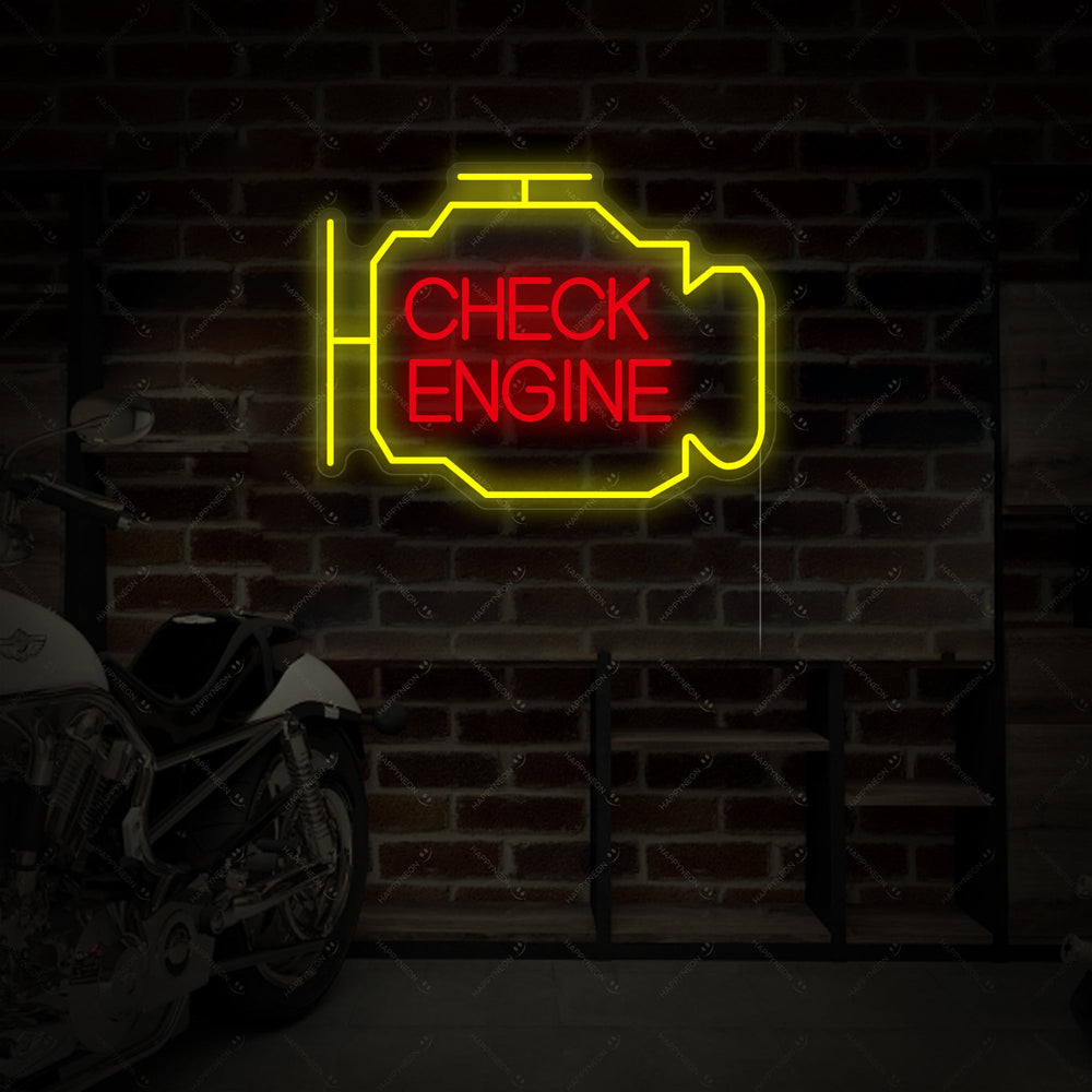 An angled view of an amber 'Check Engine' neon sign mounted on a dark grey brick wall in a garage, with a motorcycle visible in the background.