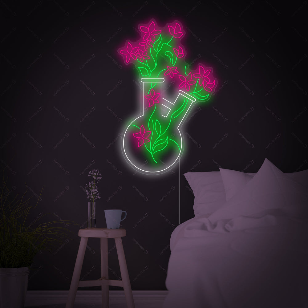 A brightly lit chemistry beaker vase neon sign displaying a vibrant blue beaker outline with green plant leaves inside, glowing against a simple background.