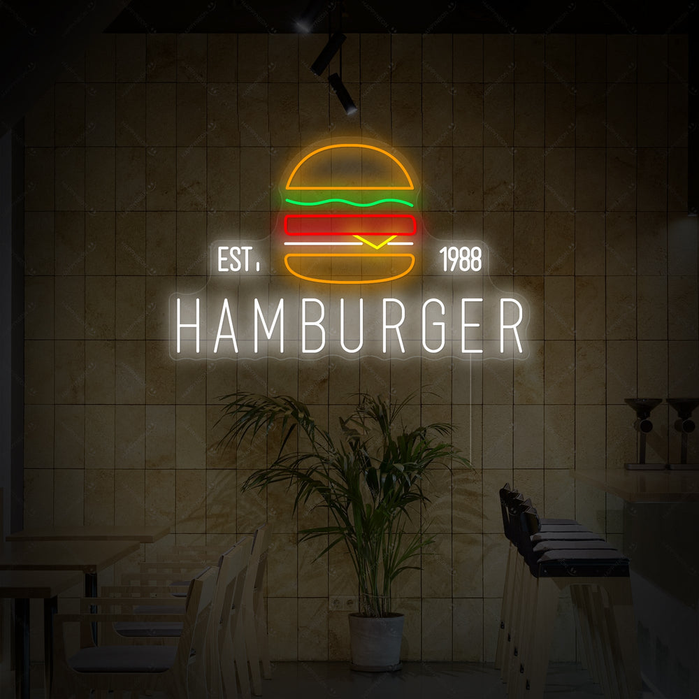 A glowing neon sign depicting a detailed hamburger, mounted on a rustic wooden wall above a restaurant booth.