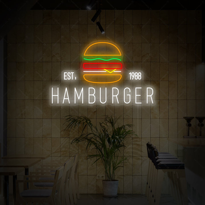A glowing neon sign depicting a detailed hamburger, mounted on a rustic wooden wall above a restaurant booth.