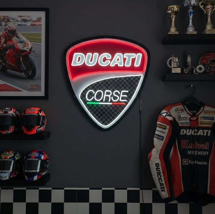 A Ducati neon sign glowing red on a wooden wall above a workbench with tools.