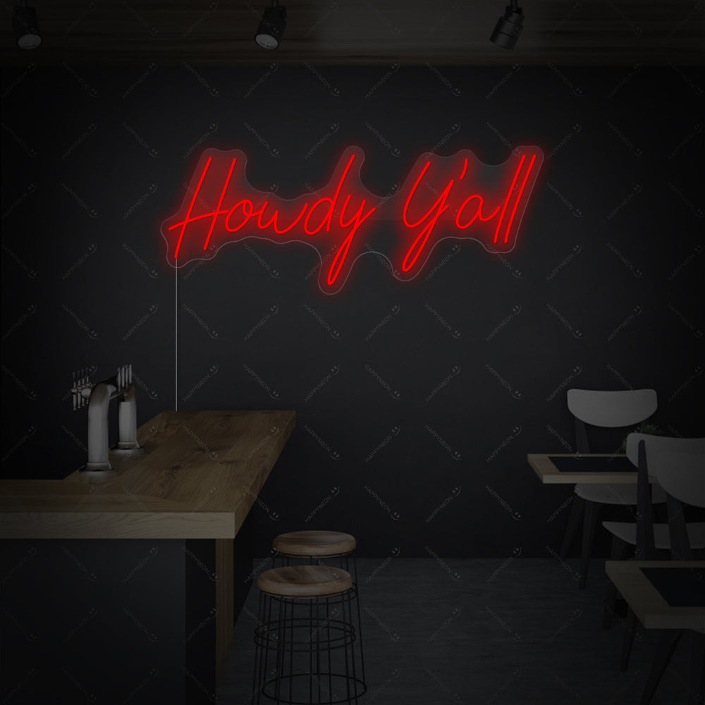 The 'Howdy Y'all' neon sign glowing in bright yellow, mounted on a clear acrylic backing which is cut to shape around the cursive text.