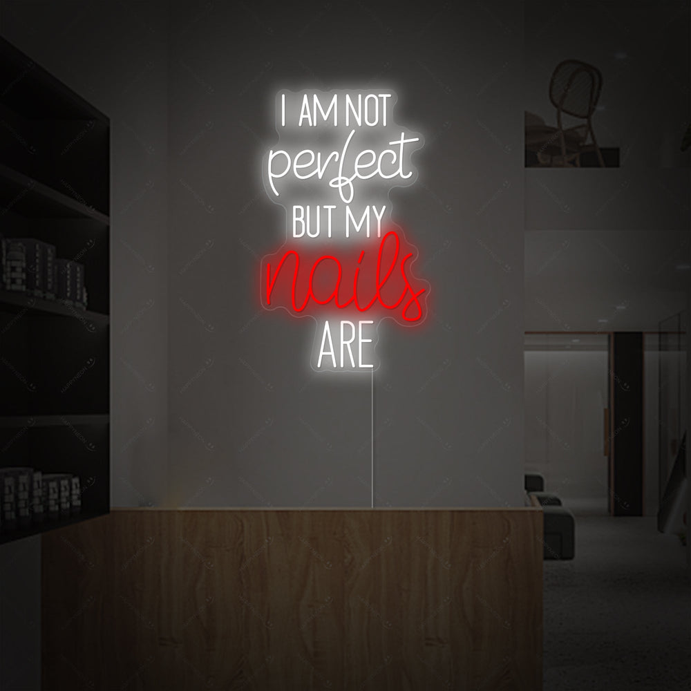 'I Am Not Perfect But My Nails Are' glowing neon wall sign mounted on a clean white wall with visible mounting details and power cord.