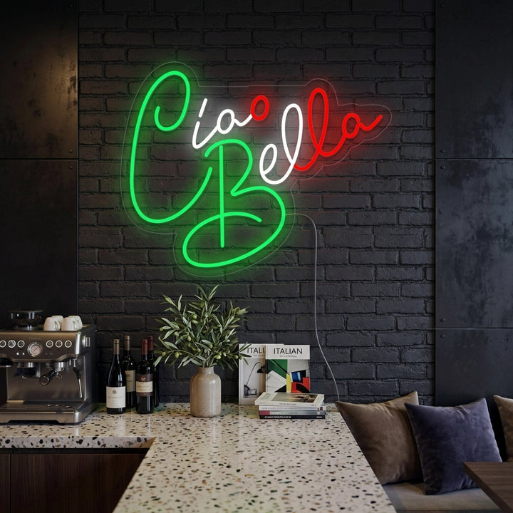 Ciao Bella Hello Beautiful illuminated neon sign mounted on a textured brick wall in a cozy living room, glowing warmly above a sofa with soft ambient lighting.